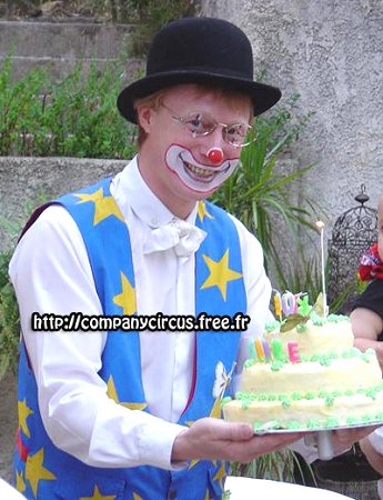 Clown au goûter d'anniversaire pressente le gâteau au public après son spectacle fort sympathique